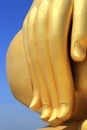 Fingers of biggest golden buddha statue on blue sky background