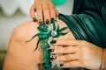 Fingers of the bride, with a beautiful manicure, keep on her leg a wedding garter Royalty Free Stock Photo