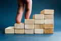 Fingers climbing the stairs made with wooden blocks. Concept of the success, career, goal achievement, hardworking.