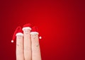 Fingers faces in Santa hats against red background