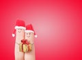 Fingers faces in Santa hats with gift box. Happy couple