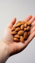 Fingers grasp a single almond from a clean white surface, nutty delight