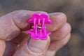 fingers on hand hold pink plastic clip