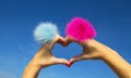 Fingers heart with blue and pink rings with fur on blue sky background