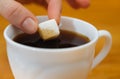 Fingers hold a lump sugar piece over cup of tea Royalty Free Stock Photo