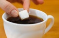 Fingers hold a lump sugar piece over cup of tea Royalty Free Stock Photo