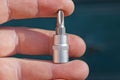 Fingers hold one gray metal adapter with a screwdriver