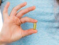 Fingers holding a fish oil capsule Royalty Free Stock Photo