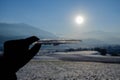 Fingers holding ice surrounded by mountains under the sunlight with a blurry background Royalty Free Stock Photo
