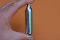 Fingers holding one gray metal balloon for a pneumatic pistol