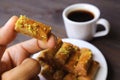 Fingers Holding a Pistachio Nuts Baklava Pastries with Blurry Turkish Coffee and a Plate of Sweets in Background Royalty Free Stock Photo