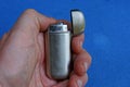 Fingers holds a gray metal lighter