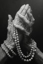 Fingers intertwined with rosary beads representing faith