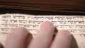 Fingers on page of old book Torah. Selective focus on snippet Hebrew Bible text: offer the Passover sacrifice to Jehovah