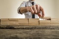 Fingers placing wooden block on orderly stack