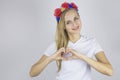 Fingers in the shape of a heart. Girl in a national wreath on her head