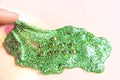 Fingers stretch green glitter slime and golden letters Love Slime, partial blur