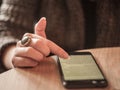 Fingers of a young white caucasian woman browsing a smartphone with 3G internet displaying a wide screen full of text