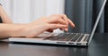 Fingers of young woman typing on laptop keyboard. Unrecognised hands typing on computer keyboard. Close up of keyboard. Business c