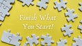 Finish what you start text on yellow background with white jigsaw puzzle missing pieces. Royalty Free Stock Photo