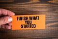 Finish What You Started. An orange card with a text in a man& x27;s hand