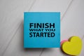 Finish What You Started write on a sticky note on Office Desk