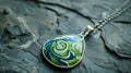 A finished ceramic pendant adorned with delicate swirls of blue and green glaze dangling from a sterling silver chain.