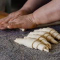 Finished production raw croissants in factory in the steel table. Production of bread, closeup. Working process. Private bakery.