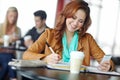 Finishing her assignment on the go. A beautiful young university student using her smartphone in a coffeee shop while Royalty Free Stock Photo