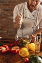 Young Caucasian red-bearded man, chef cooking fresh vegetable salad in cafe, restaurant kitchen. Concept of a correct Royalty Free Stock Photo