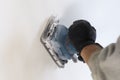 . Finishing work - the master aligns the wall with a sander, it has dust on which it works. there is tanirovanie Royalty Free Stock Photo