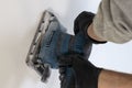 . Finishing work - the master aligns the wall with a sander, it has dust on which it works. there is tanirovanie Royalty Free Stock Photo