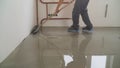 A worker rolls out the liquid floor with a trowel. Squeegee for distributing the mixture. The worker levels the liquid