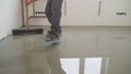 A worker rolls out the liquid floor with a trowel. Squeegee for distributing the mixture. The worker levels the liquid