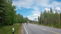 Finland. View of a scenic road passing through a forest. Beautiful Scandinavian landscape. Deer cross the road