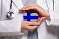 Finnish doctor holding heart with flag of Finland background. Healthcare, charity, insurance and medicine concept Royalty Free Stock Photo