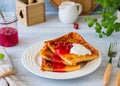 Finnish pancake pannukakku with redcurrant jam and sour cream or whipped cream on a white ceramic plate on a light wooden Royalty Free Stock Photo