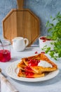 Finnish pancake pannukakku with redcurrant jam and sour cream or whipped cream on a white ceramic plate on a light wooden Royalty Free Stock Photo