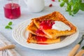 Finnish pancake pannukakku with redcurrant jam and sour cream or whipped cream on a white ceramic plate on a light wooden Royalty Free Stock Photo