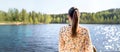 Finnish woman standing and looking at a lake in Finland. Happy person relaxing and enjoying sunny summer vacation or weekend. Royalty Free Stock Photo