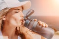 Fintess woman drinking water. Happy, active middle aged woman standing on beach and drinking water after excersise Royalty Free Stock Photo