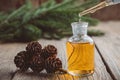 Fir aromatic oil in a glass dropper bottle, a drop of pine essential oil dripping from glass dropper.