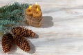 Fir branch, burning candles, cones on a white wooden background