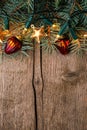 Fir branch with Christmas decorations and glowing garland on old wooden background with empty space for text. Top view Royalty Free Stock Photo