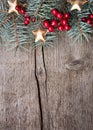 Fir branch with red berries and golden stars on an old wooden board with copy space for text. Christmas and New Year holidays back Royalty Free Stock Photo