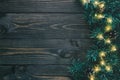 Fir branches and christmas lights on dark wooden background with copy space. Flat lay, top view Royalty Free Stock Photo