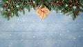 Fir Branches and Christmas Ornament with Gift on snowy blue wood plank