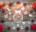 Fir branches with red bows, and xmas handmade toys and balls creating a circle on a wooden gray background