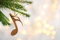 Fir tree branch with wooden note against blurred lights. Christmas music Royalty Free Stock Photo