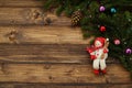Fir tree branches with Christmas decoration and toy snowman against old vintage style wooden planks. Christmas/New Year concept. Royalty Free Stock Photo